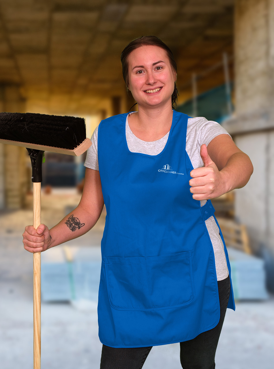Eine Mitarbeiterin der Baureinigung München auf einer Baustelle mit Besen und Daumen hoch