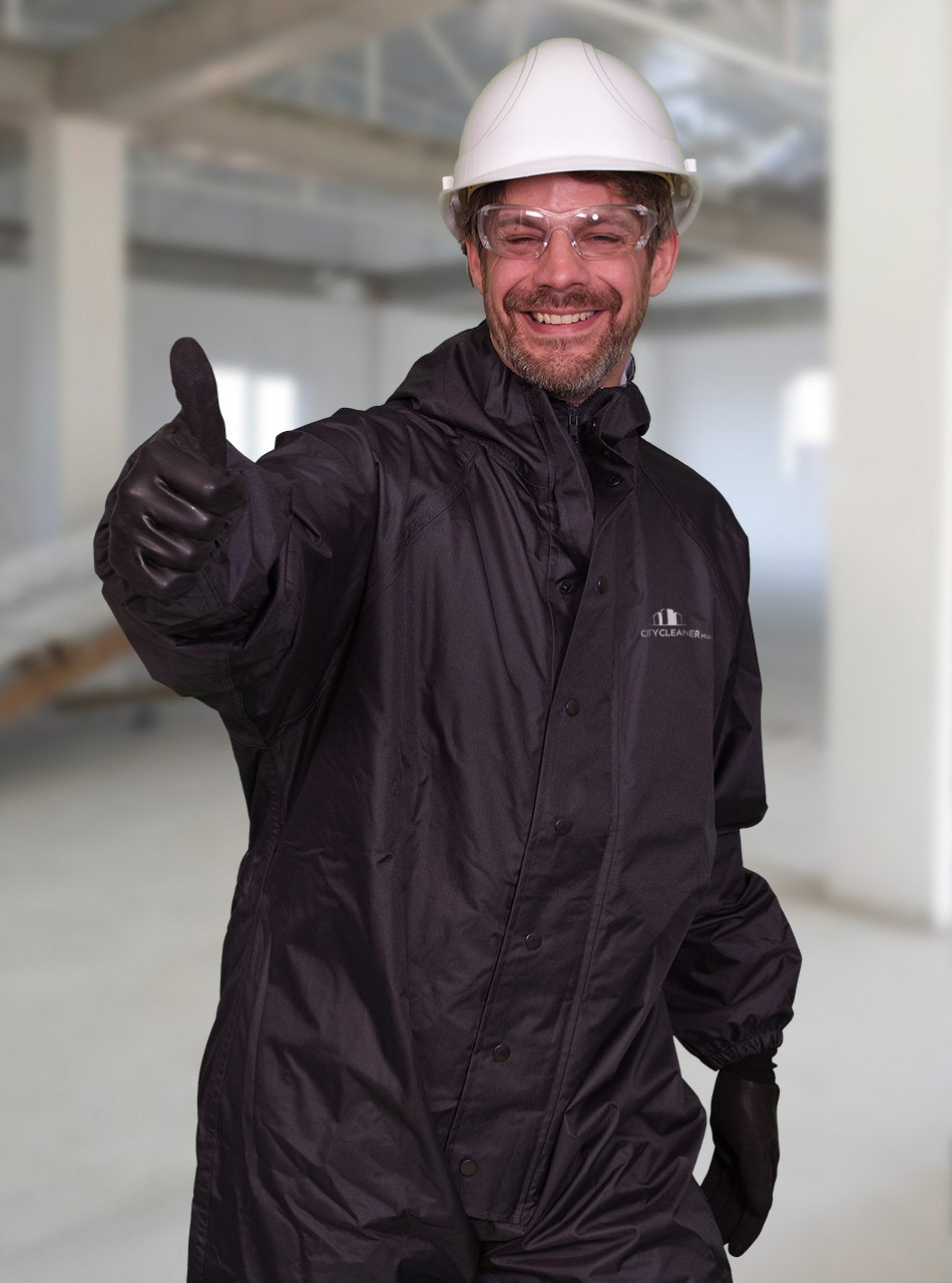 Ein Mitarbeiter der Baureinigung München mit einem Bauhelm und Daumen hoch