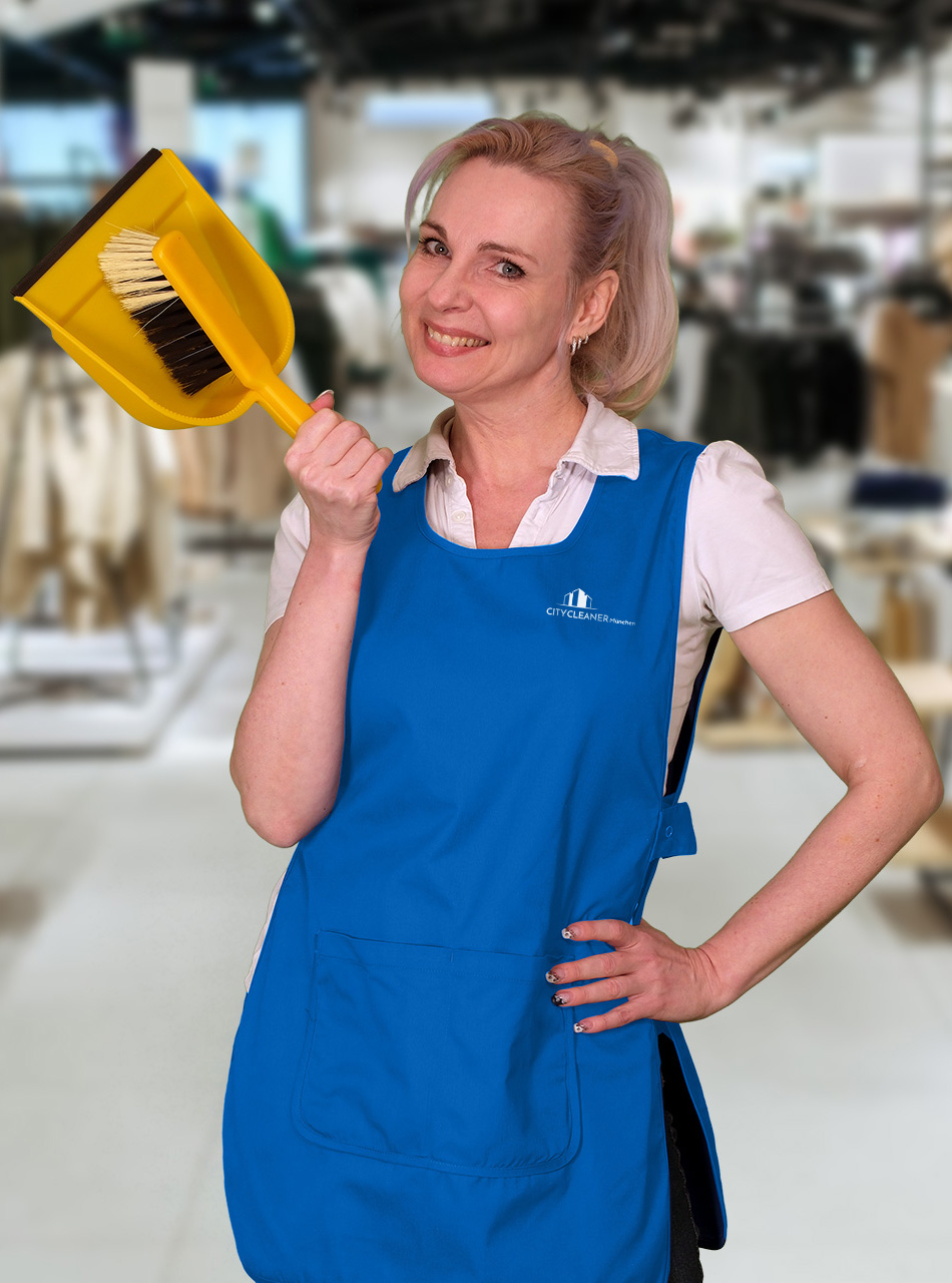 Eine Mitarbeiterin der Einzelhandelsreinigung München mit blauer Weste und Kehrbesen