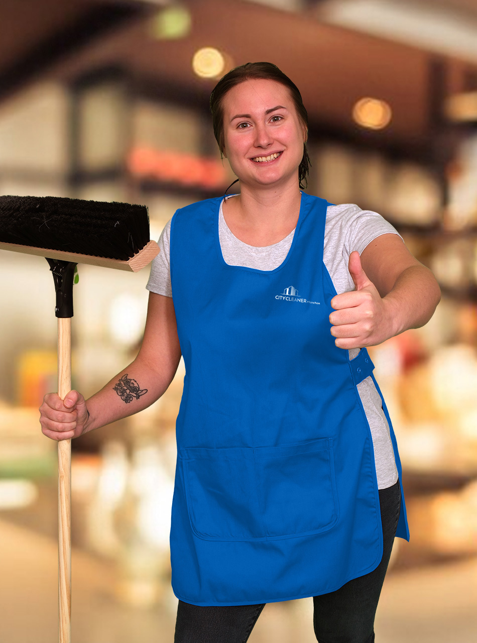 Eine Mitarbeiterin der Einzelhandelsreinigung München mit blauer Weste, Besen und Daumen noch