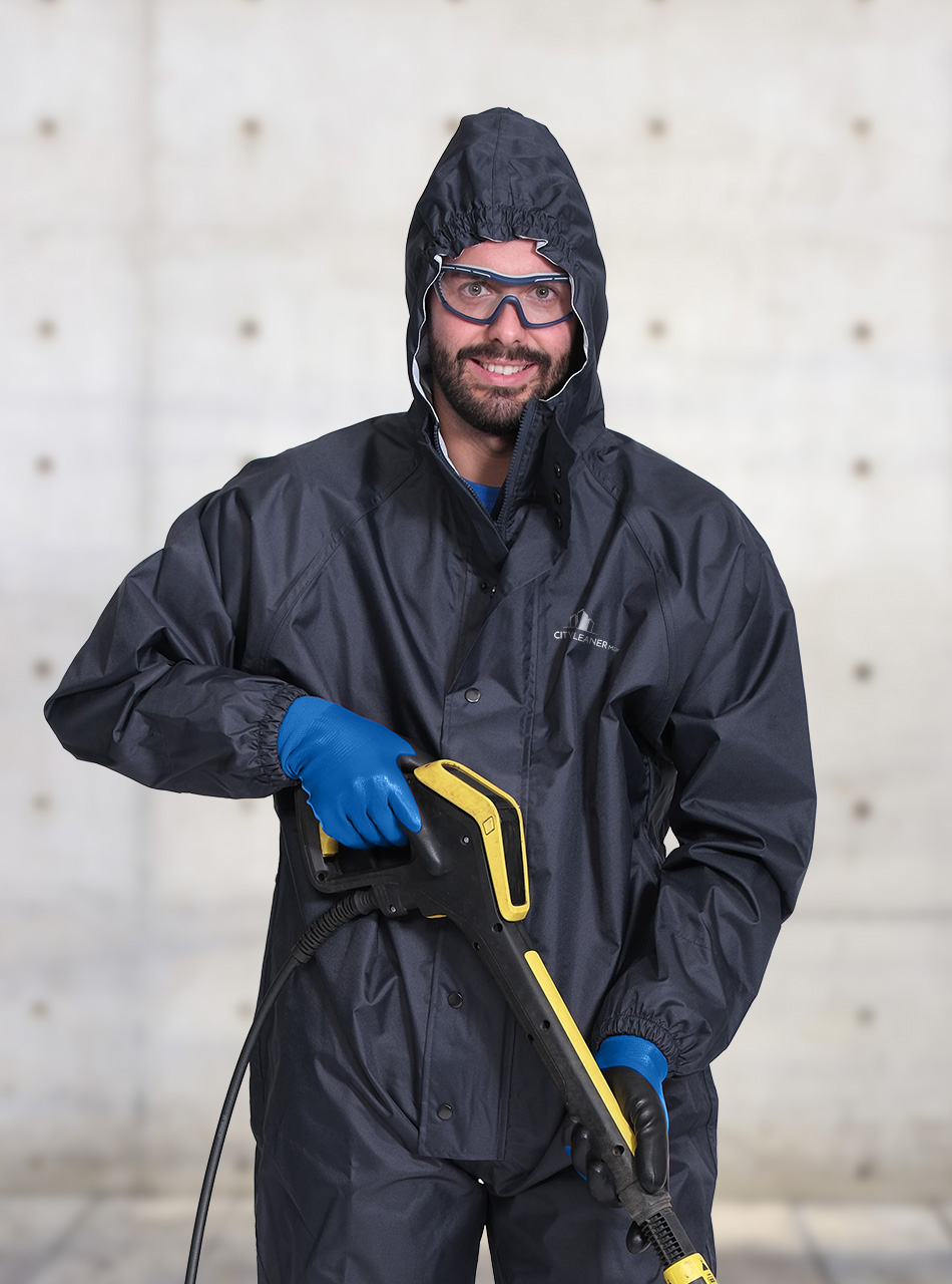 Ein Mitarbeiter der Fassadenreinigung München im schwarzen Overall mit Hochdruckreiniger