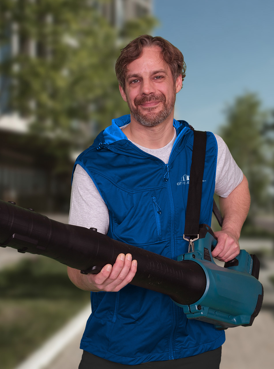 Ein Mitarbeiter der Hausmeisterservice München mit blauer Weste und Laubbläser