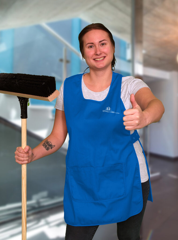Eine Mitarbeiterin der Reinigungsfirma München mit blauer Weste und Daumen hoch